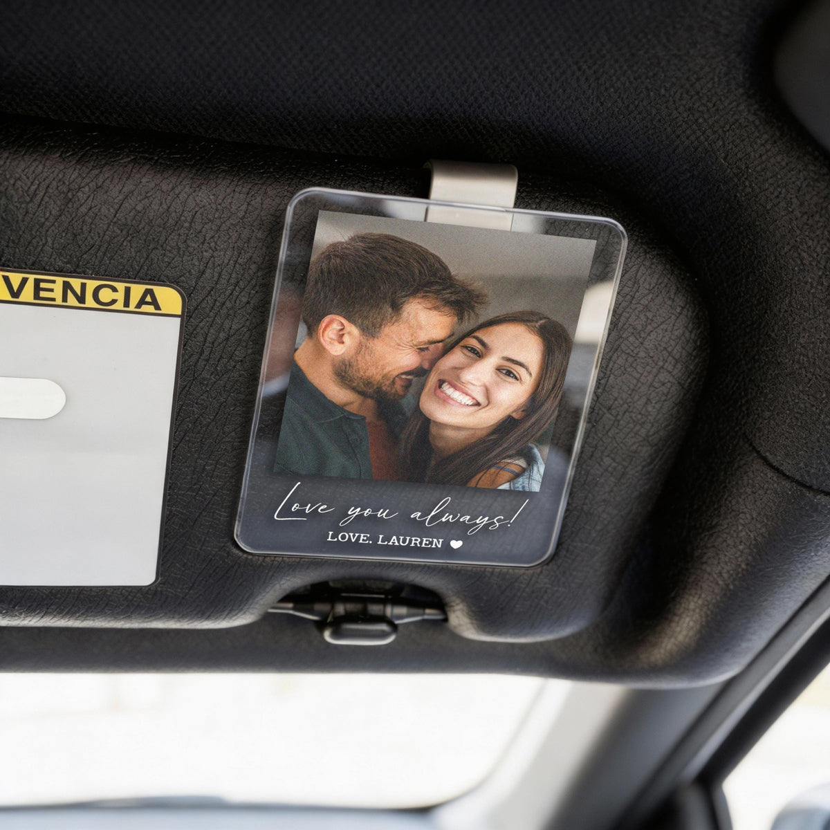 Clear acrylic car visor photo holder with a printed photo of a smiling couple. The holder has the text "Love you always!" and "LOVE, LAUREN" in a handwritten style font.