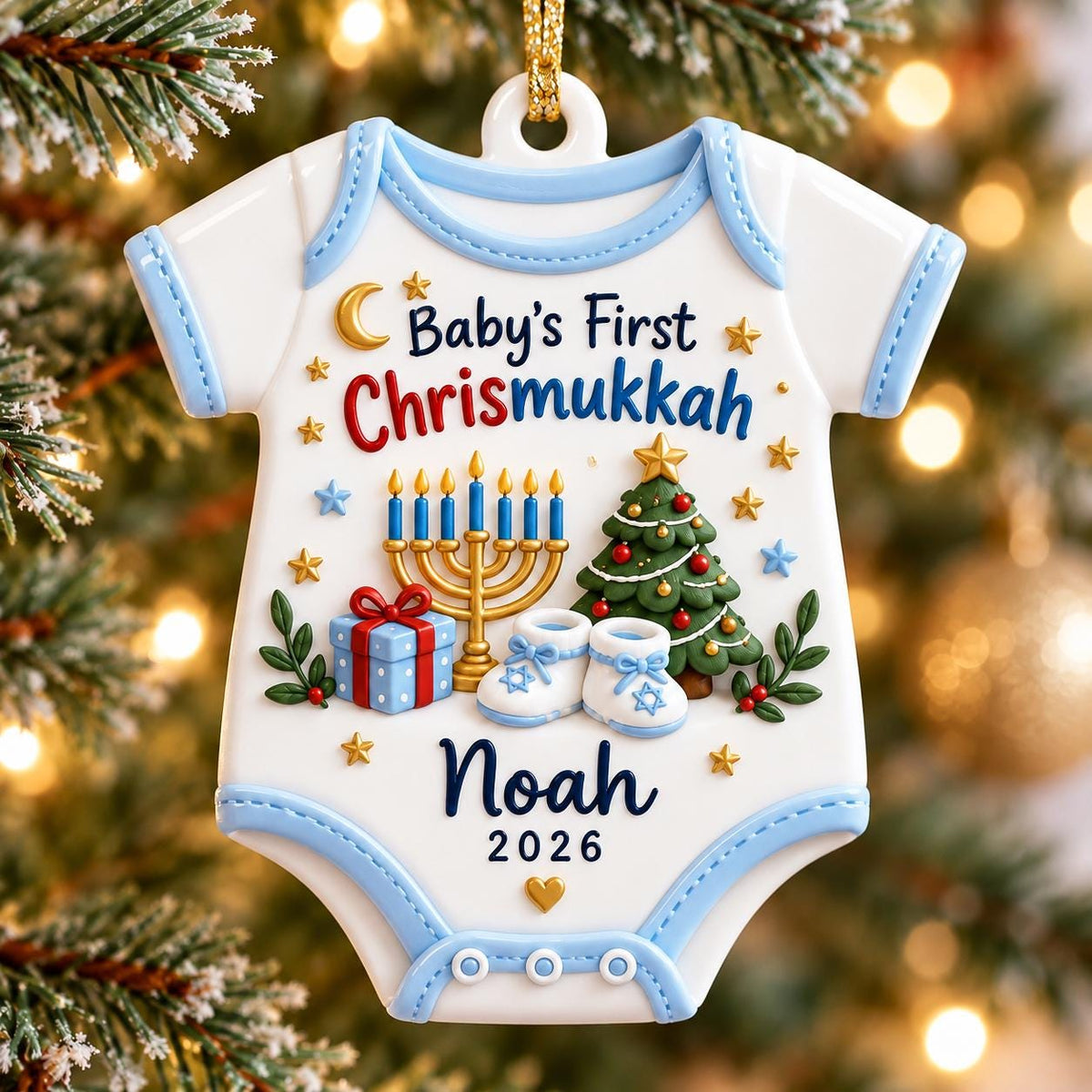 May include: A white baby bodysuit-shaped Christmas ornament with light blue trim. It features the text "Baby's First Chrismukkah", a gold menorah, a decorated Christmas tree, a blue gift box, and baby booties. The name "Noah" and "2026" are printed.