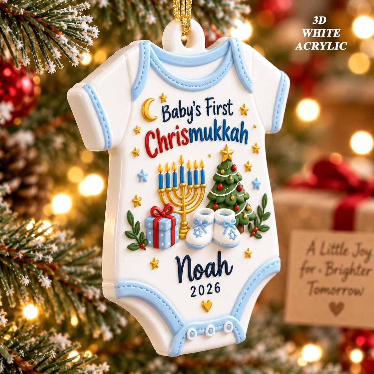 May include: A 3D white acrylic baby onesie ornament with light blue trim. It features the text Baby's First Chrismukkah, Noah, and 2026. Graphics include a gold menorah, a green Christmas tree, a blue gift box, and white baby booties with stars.