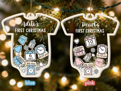 May include: Two baby onesie-shaped Christmas ornaments. One is blue and says "Aditi's FIRST CHRISTMAS" with birth details. The other is pink and says "Pearl's FIRST CHRISTMAS" with birth details. Both have snowflake accents.