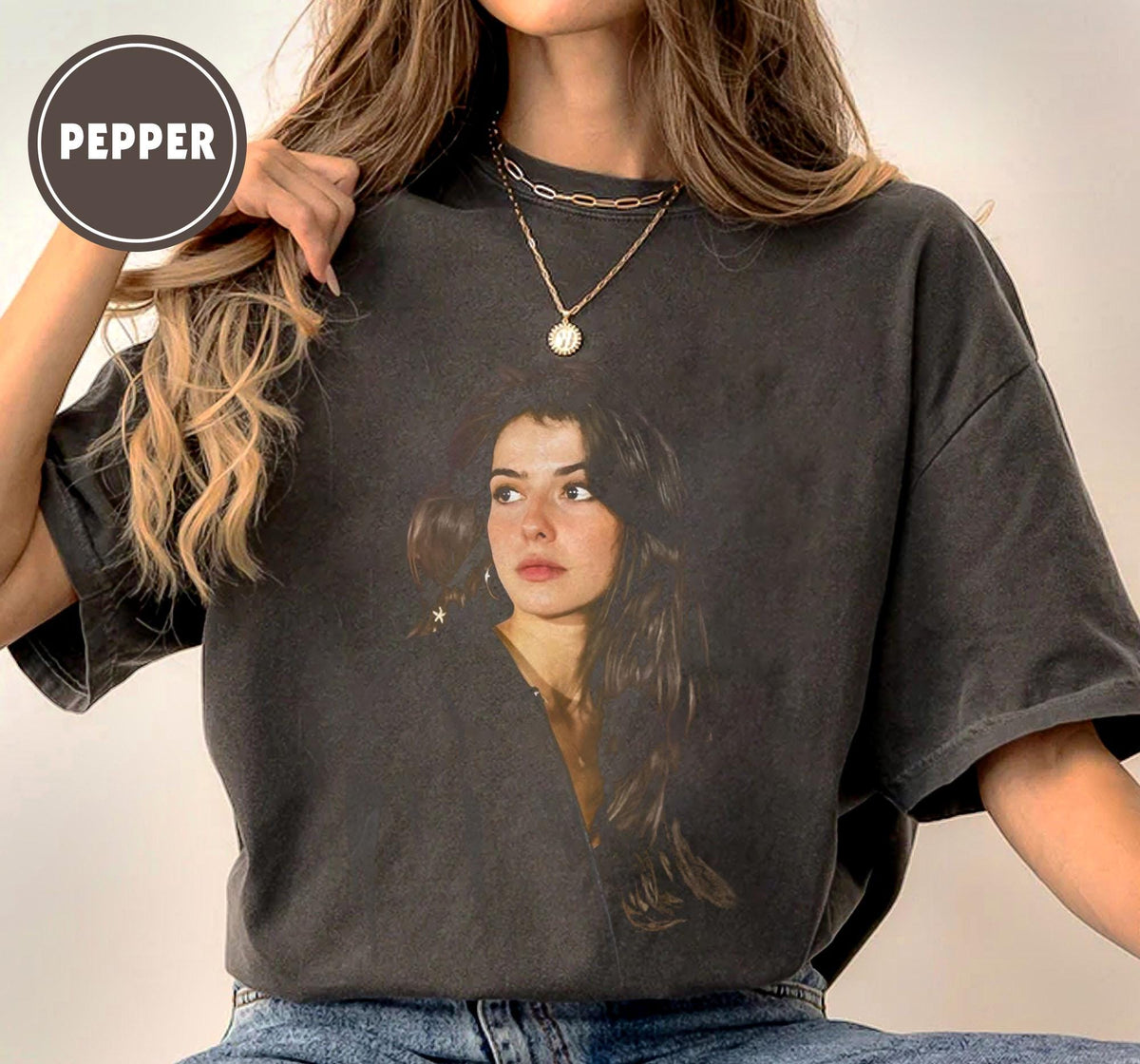 Dark gray t-shirt featuring a portrait of a woman with long dark hair. The shirt has a vintage, faded look. The word "PEPPER" is printed in a circle at the top left.