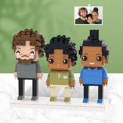 Three custom brick-built figures standing on a white rectangular base. The left figure has brown hair and a beard in a gray shirt. The middle figure has black hair in a green shirt. The right figure has black hair in a blue shirt.