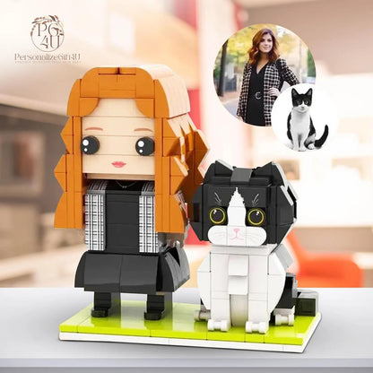 A custom brick-built figurine set featuring a person with long orange hair wearing a black dress and a plaid jacket, standing next to a black and white cat. The figures are mounted on a rectangular light green base plate.