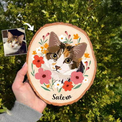 May include: A wooden slice featuring a painted portrait of a cat with brown, white, and orange fur, surrounded by pink, orange, and white flowers. The cat's name, "Salem," is written in black script below the portrait.