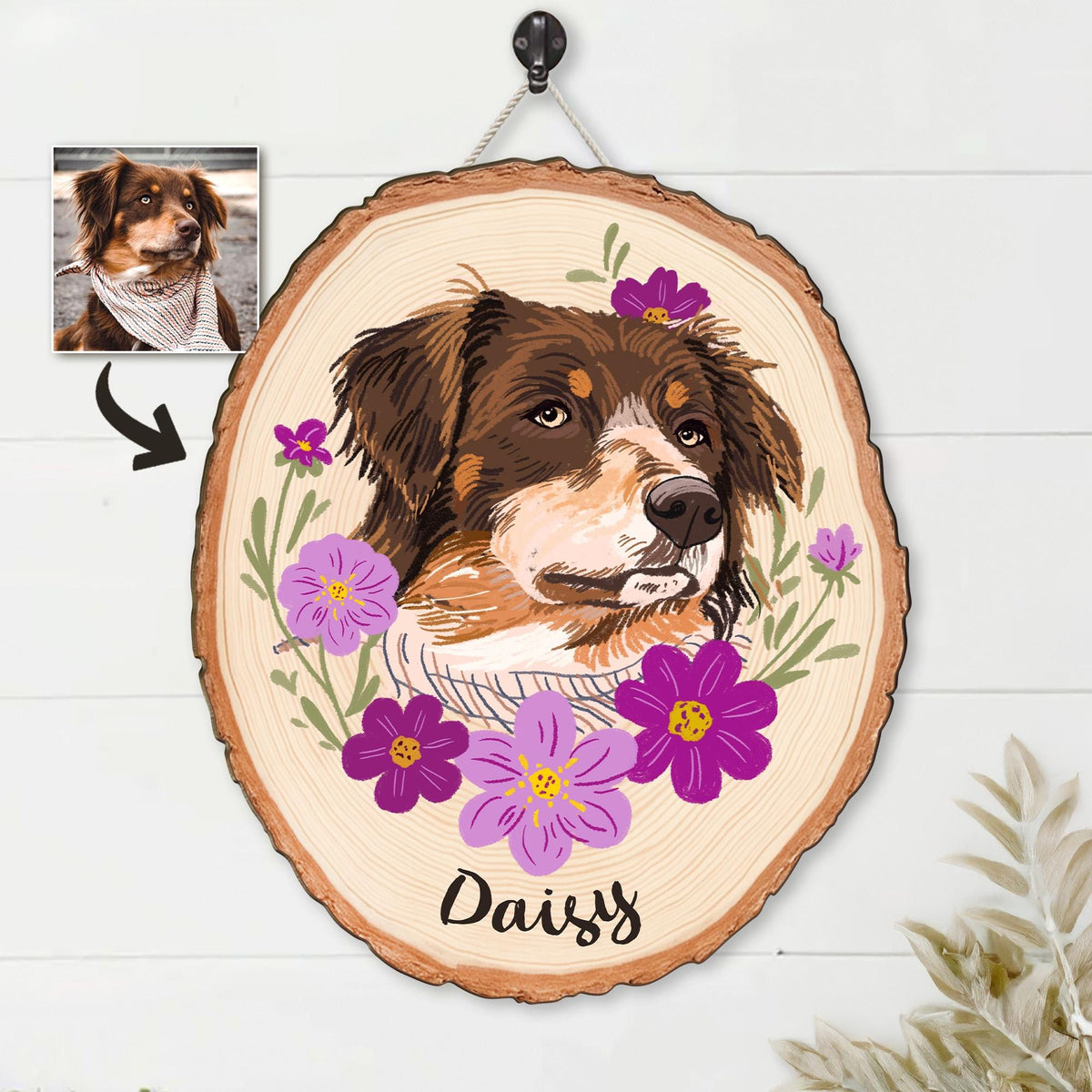 May include: A wooden pet portrait featuring a brown and white dog with a floral design. The dog's name, "Daisy", is written in cursive below the portrait. The portrait is on a wood slice and is hanging from a rope.