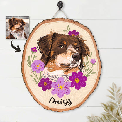 May include: A wooden pet portrait featuring a brown and white dog with a floral design. The dog's name, "Daisy", is written in cursive below the portrait. The portrait is on a wood slice and is hanging from a rope.