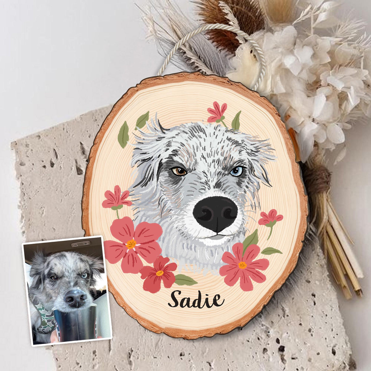 May include: A wooden slice featuring a hand-painted portrait of a dog with heterochromia, surrounded by red flowers and green leaves. The dog's name, "Sadie," is written in black script. A smaller photo of the dog is in the lower left corner.
