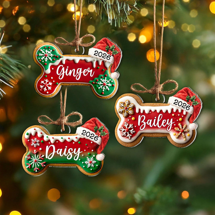 May include: Three bone-shaped Christmas ornaments featuring red and green icing, white snowflake details, and a Santa hat with the year 2026. Each ornament is personalized with the names Ginger, Bailey, or Daisy and hangs from a brown twine loop.