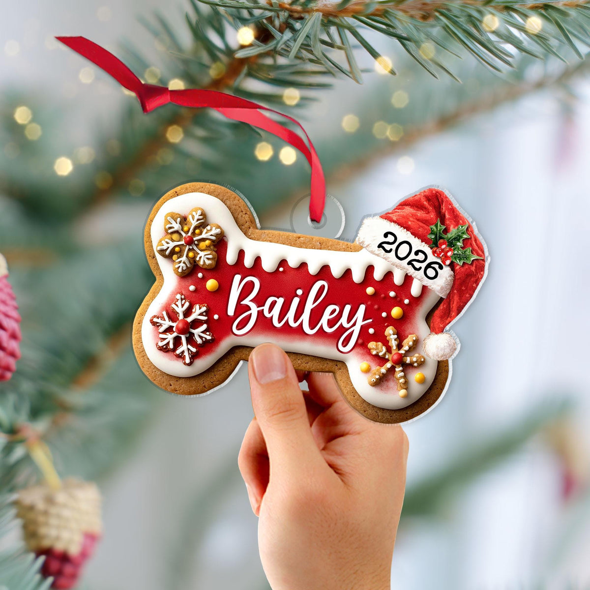 May include: A bone-shaped Christmas ornament featuring a red center with the name Bailey in white script, white icing-style borders, three snowflake decorations, and a red Santa hat with the year 2026 printed on it, suspended by a red ribbon.