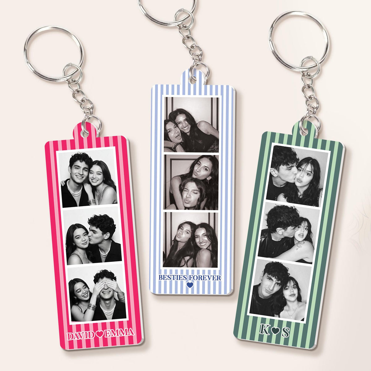 Three rectangular acrylic keychains with metal rings, each featuring a vertical striped border in pink, blue, or green. Each keychain displays three black and white photo strips. Text includes DAVID HEART EMMA, BESTIES FOREVER HEART, and K HEART S.
