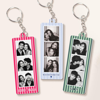 Three rectangular acrylic keychains with metal rings, each featuring a vertical striped border in pink, blue, or green. Each keychain displays three black and white photo strips. Text includes DAVID HEART EMMA, BESTIES FOREVER HEART, and K HEART S.