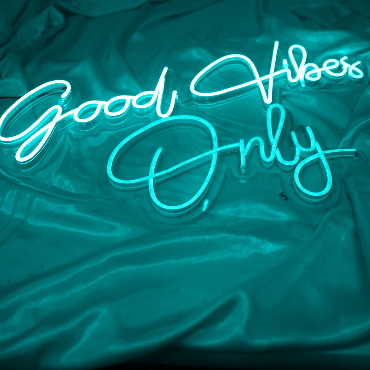 Neon sign with the words "Good Vibes Only" in white letters on a teal blue background.