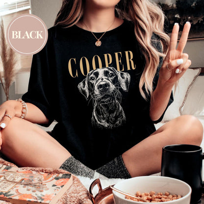 Black t-shirt featuring a detailed illustration of a dog's face with the name "COOPER" in gold lettering above. A circular "BLACK" label is in the upper left corner. The shirt is a casual style.