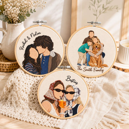 Three circular embroidery hoops featuring custom thread portraits on off-white fabric. One shows a couple with the text Rachel & Nolan, another a family with a dog labeled The Smith Family, and the third two people labeled Besties.