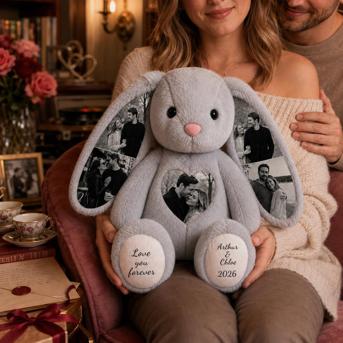 A plush gray rabbit toy featuring long ears printed with black and white photographs of a couple. A heart-shaped patch on the chest displays a photo of a couple. The white foot pads are embroidered with the text Love you forever and Arthur & Chloe 2026.