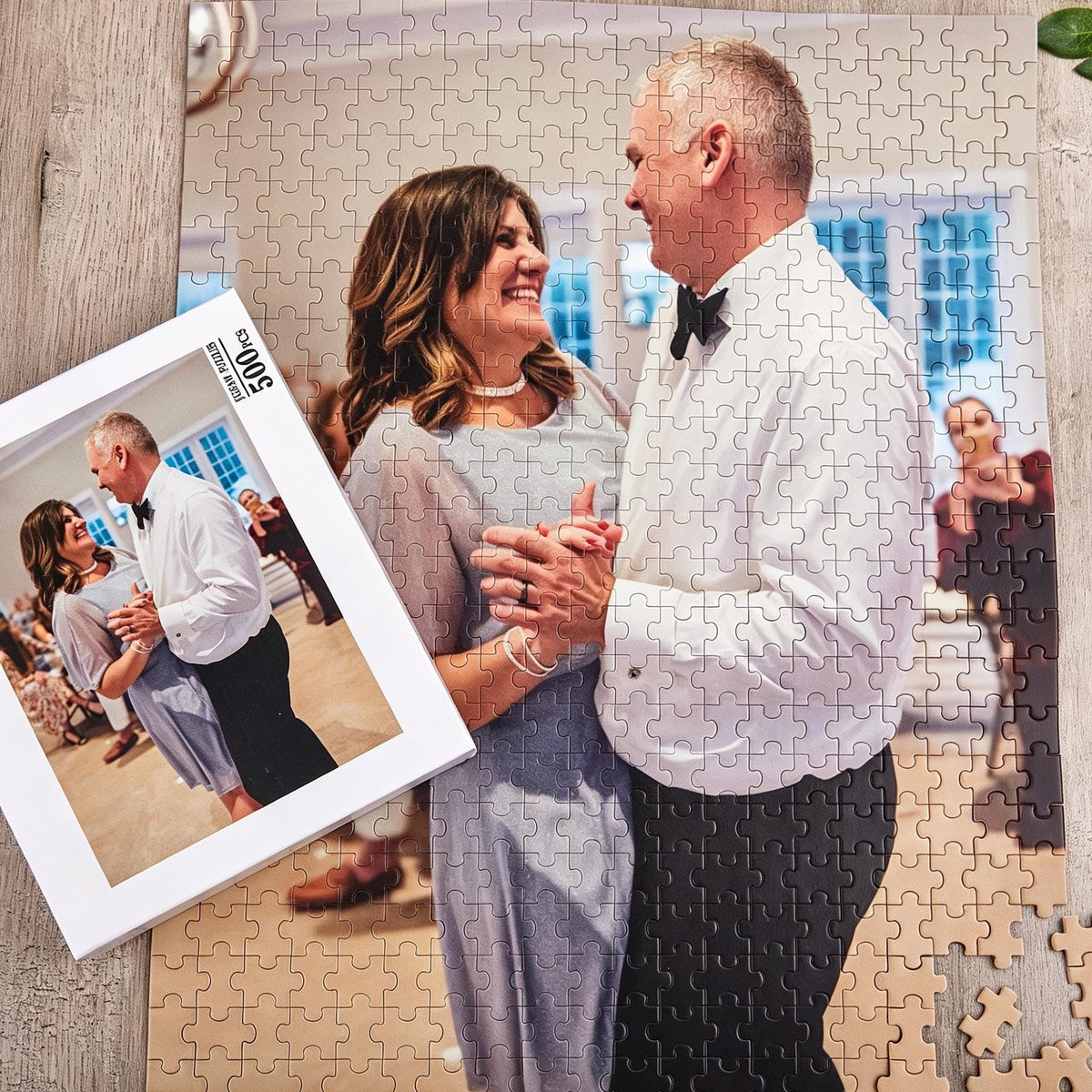 A 500-piece jigsaw puzzle featuring a photograph of a couple dancing. The person on the left wears a light blue dress, and the person on the right wears a white button-down shirt with a black bowtie and black trousers.