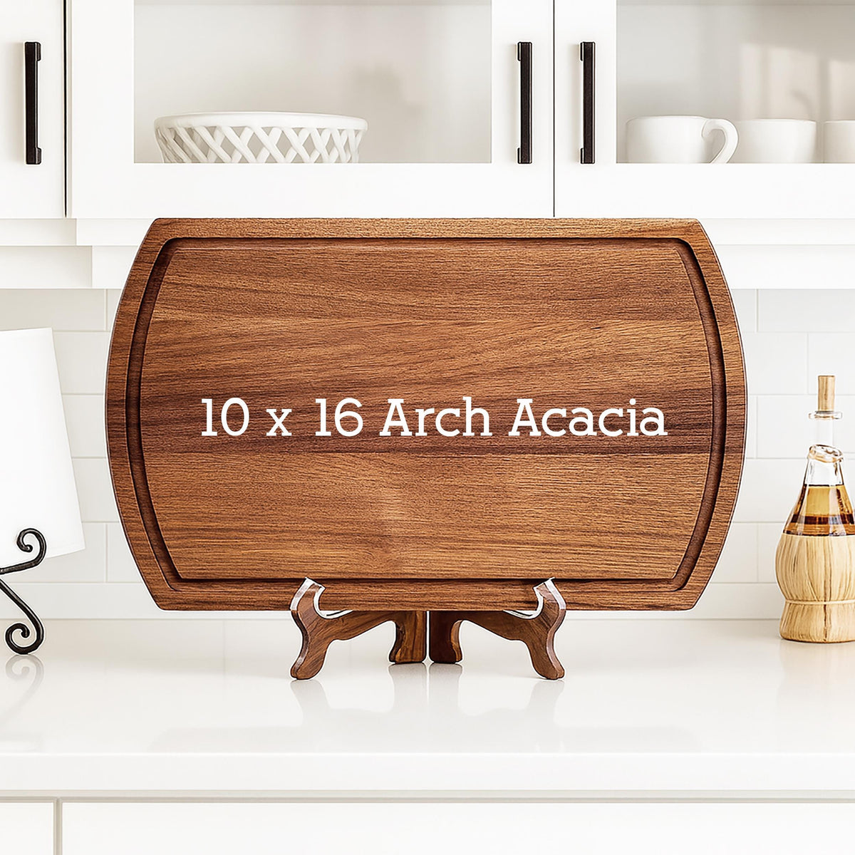 A rectangular Arch Acacia cutting board, 10 x 16 inches, with a juice groove. The board is displayed on a wooden stand. The text "10 x 16 Arch Acacia" is printed on the board.