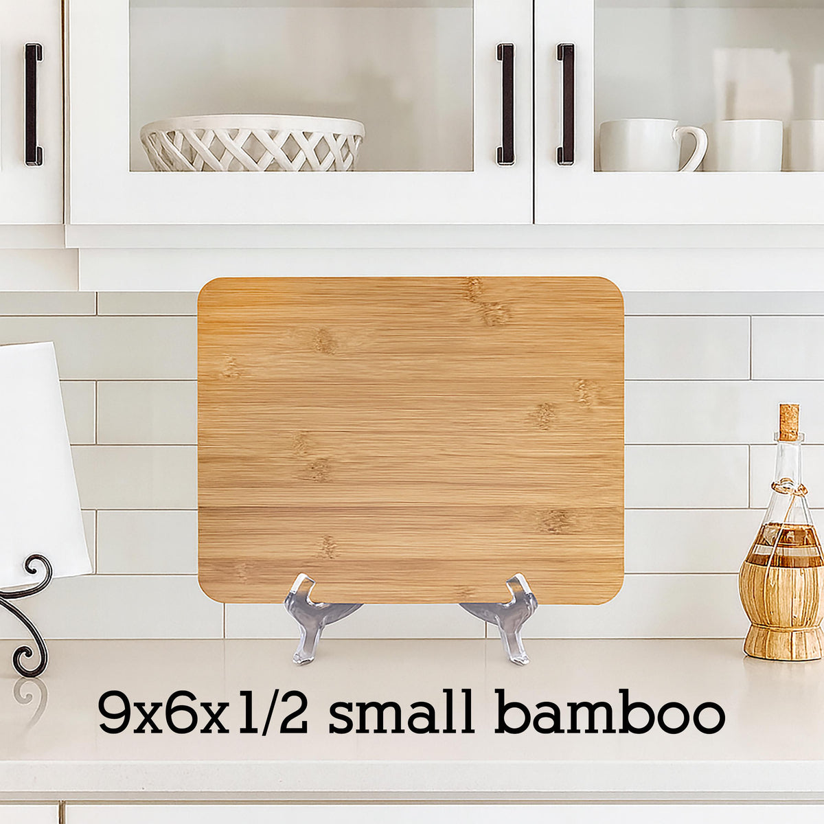 A small, rectangular bamboo cutting board, measuring 9x6x1/2 inches, displayed on a countertop. The board has a natural wood grain pattern and is supported by two silver-colored stands. The text "9x6x1/2 small bamboo" is printed below the board.