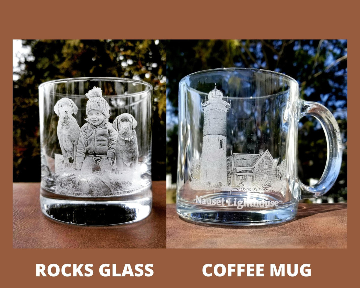 Two clear glass drinking vessels. The first is a rocks glass with an etched image of a child and two dogs. The second is a coffee mug with an etched image of a lighthouse and a building with the text "Nauset Lighthouse".