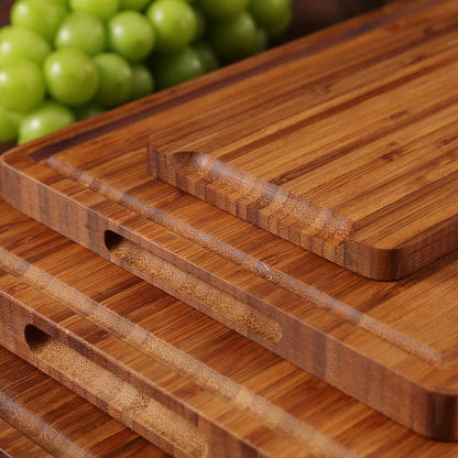 Four wooden cutting boards stacked on top of each other. The boards are made of light brown bamboo and have a smooth, polished surface. Each board has a groove around the edge and a small hole in the center.