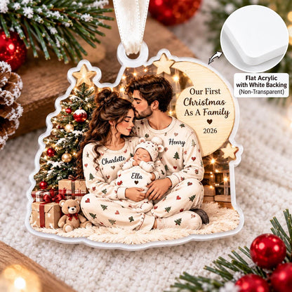 May include: A flat acrylic Christmas ornament with a white backing featuring a printed illustration of a family of three in matching pajamas sitting by a tree. The text reads Our First Christmas As A Family 2026, with names Charlotte, Henry, and Ella.