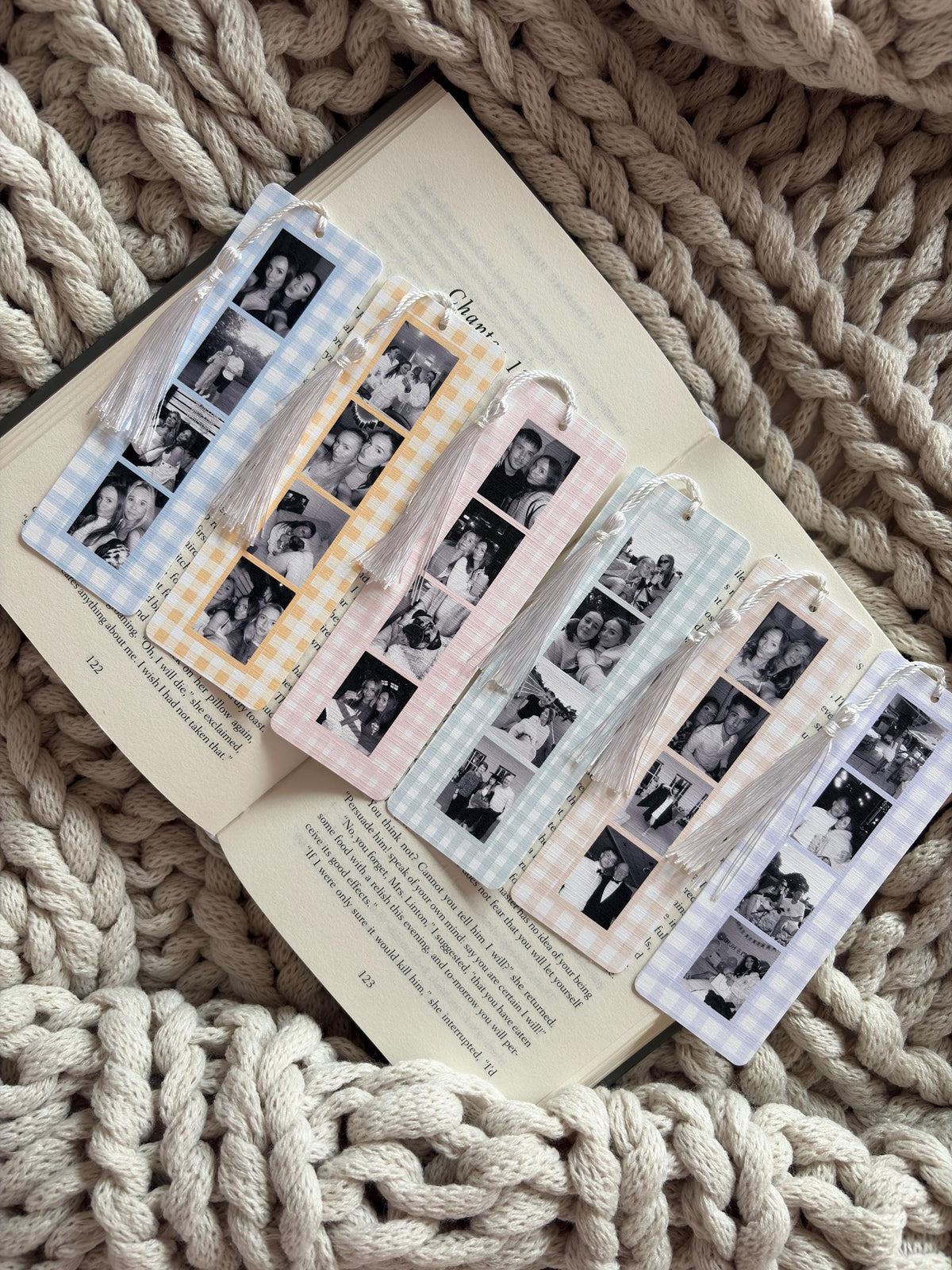 Six rectangular bookmarks with gingham borders in blue, yellow, pink, green, peach, and purple. Each bookmark features a vertical strip of black and white photo booth style images and a white tassel attached to the top with a bead.