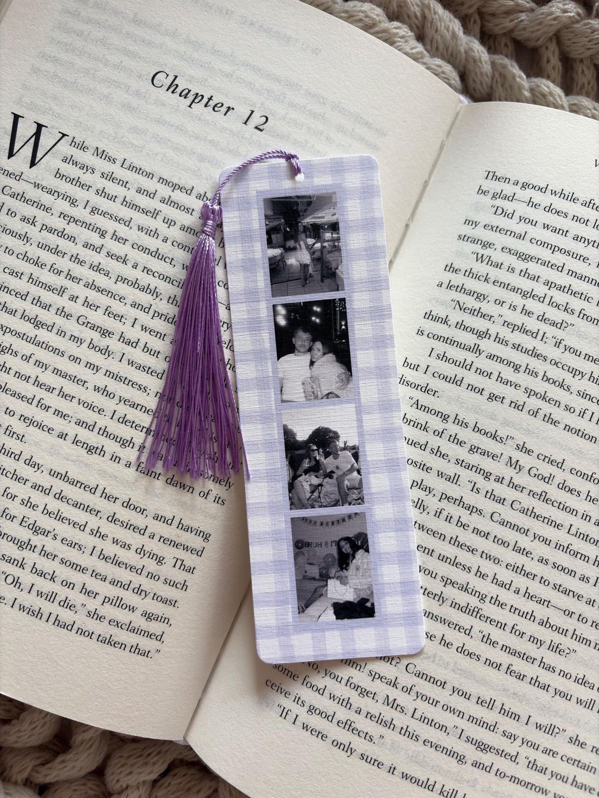 A rectangular bookmark with a light purple and white gingham pattern, featuring four vertical black and white photographs and a purple tassel attached to the top. The bookmark is placed on an open book page with printed text.