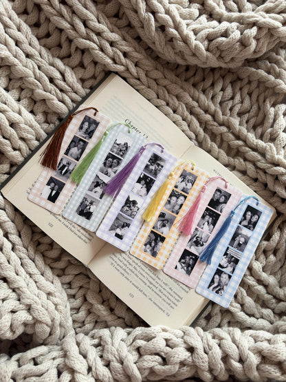 Six rectangular bookmarks with a gingham check border in various pastel colors, each featuring a vertical strip of black and white photo booth images and a matching silk tassel attached to the top hole of each bookmark.