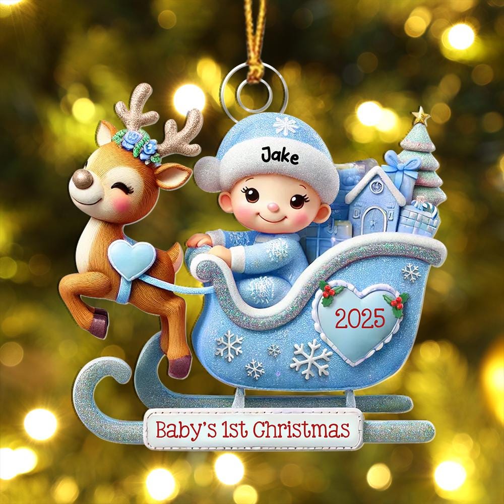 May include: A Christmas ornament featuring a brown reindeer with a blue floral crown pulling a light blue glittery sleigh. Inside the sleigh sits a baby wearing a blue hat labeled Jake. The sleigh displays the year 2025 and the text Baby's 1st Christmas.