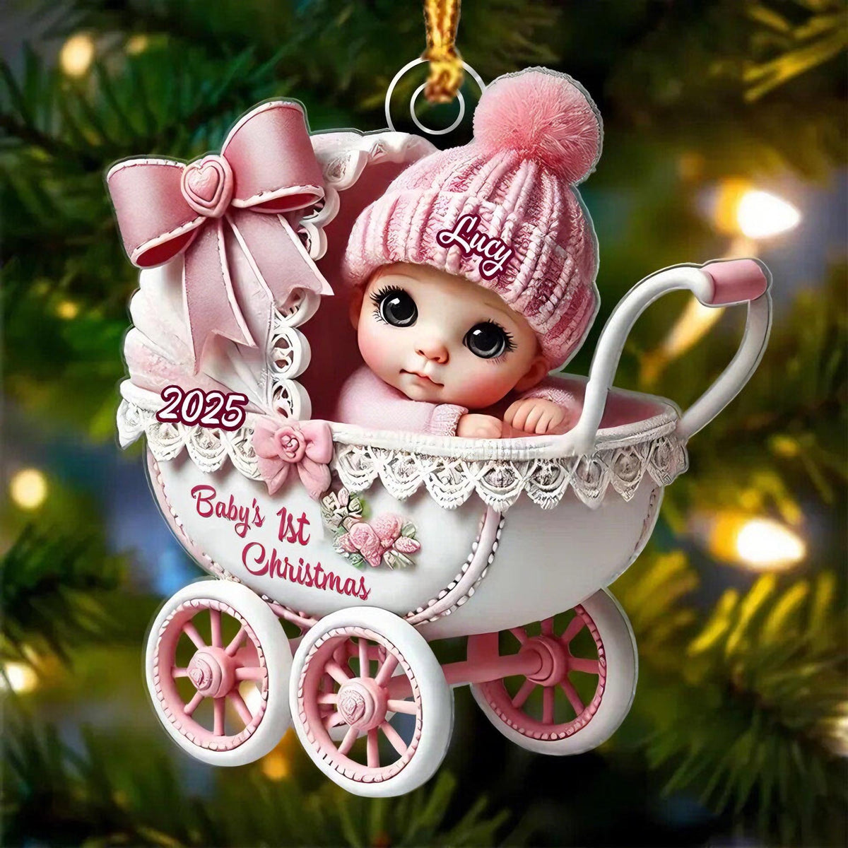 May include: A decorative Christmas ornament featuring a baby in a white and pink carriage. The baby wears a pink knit hat with the name Lucy. The carriage is adorned with a large pink bow, lace trim, and the text 2025 and Baby's 1st Christmas.