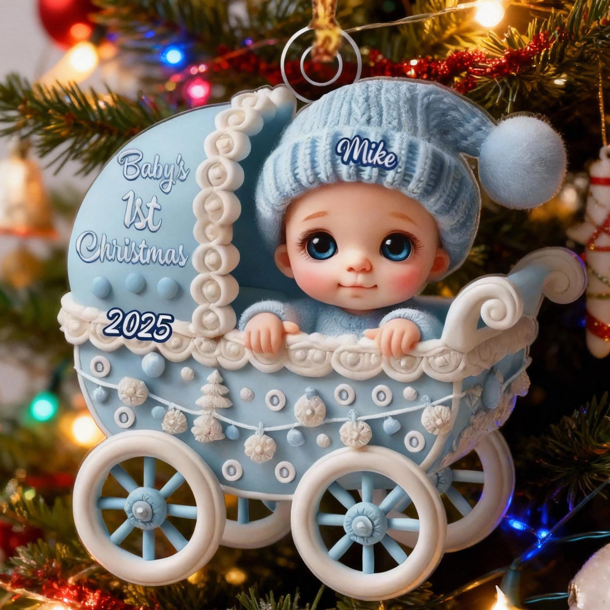 May include: A light blue baby carriage Christmas ornament featuring a baby wearing a matching blue knit hat with the name Mike embroidered on it. The carriage is decorated with white trim, snowflakes, and the text Baby's 1st Christmas 2025.