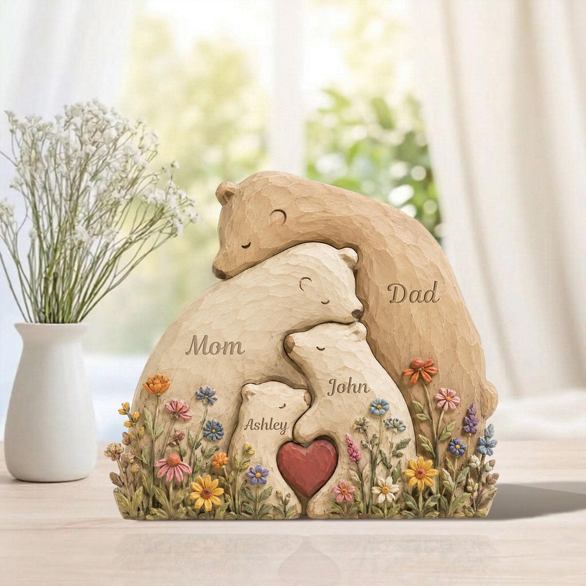 May include: A family bear sculpture with the words "Mom", "Dad", "Ashley", and "John" carved into the bears. The sculpture features a heart and is surrounded by colorful flowers. The bears are in shades of brown and cream.
