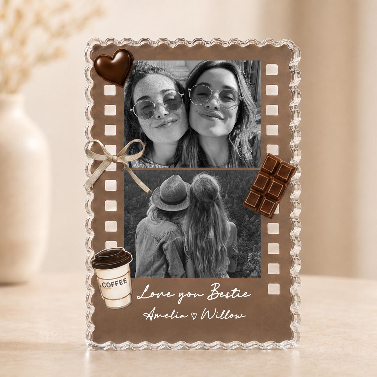 May include: A rectangular photo frame with a scalloped clear border and a brown background featuring two black and white photos of two people. Decorations include a heart-shaped chocolate, a beige ribbon, a chocolate bar, and a coffee cup. Text reads: Love you Bestie, Amelia ♡ Willow.