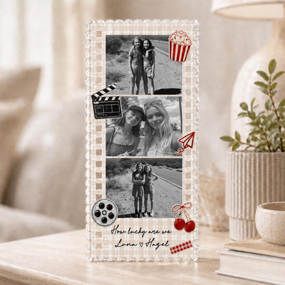 May include: A rectangular acrylic photo frame with a beige gingham border featuring three black and white photographs of two people. Decorative red icons include a popcorn bucket, film clapper, paper plane, and cherries. Text reads: How lucky are we Luna ♡ Hagel.