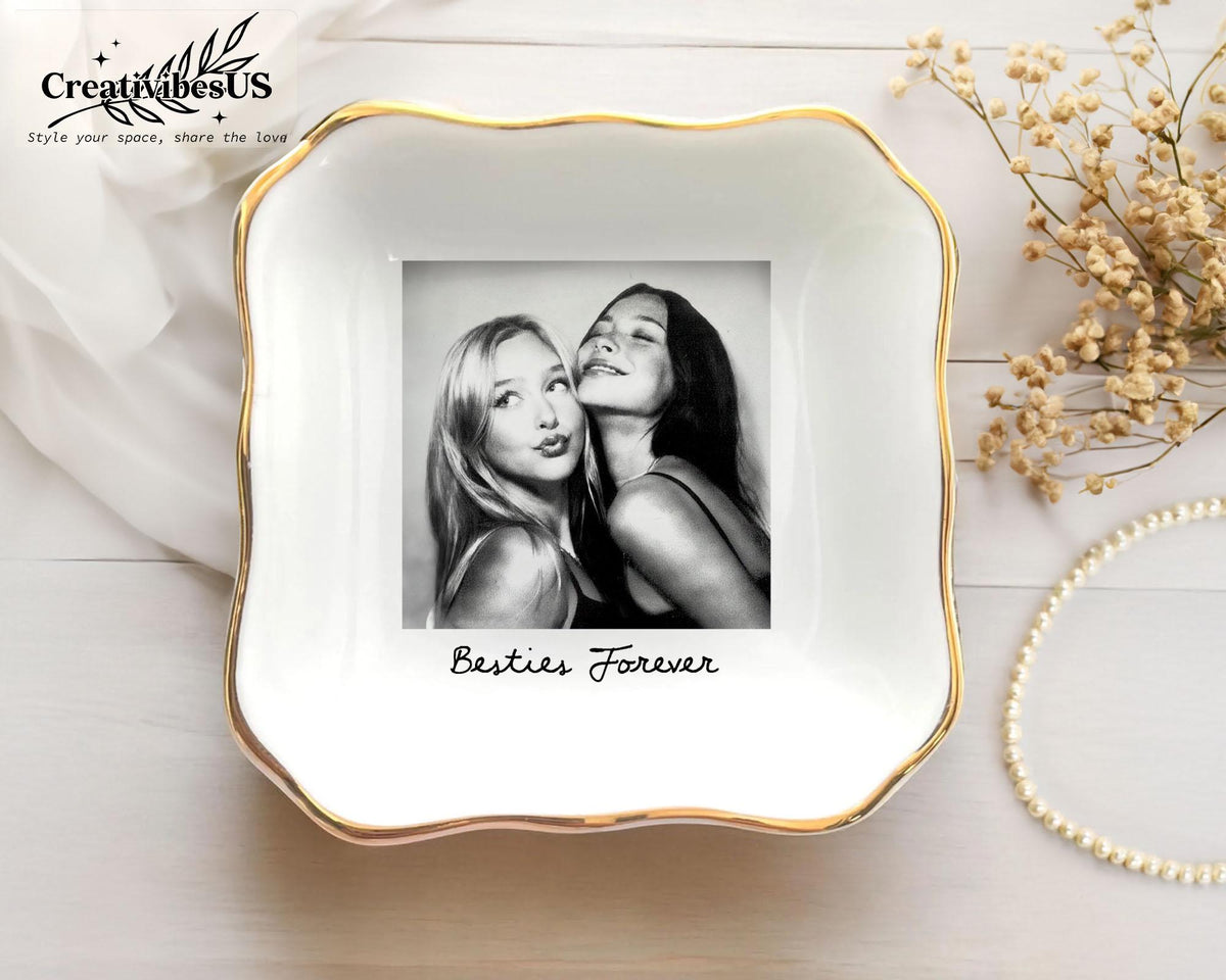 A square white ceramic trinket dish with a scalloped edge and a gold-painted rim. The center features a black and white photograph of two people with the text Besties Forever printed in black script below the image.