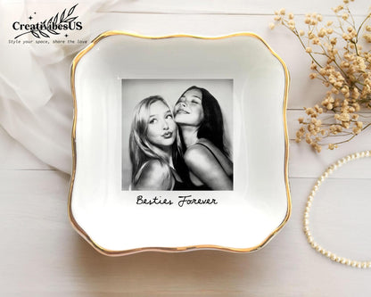 A square white ceramic trinket dish with a scalloped edge and a gold-painted rim. The center features a black and white photograph of two people with the text Besties Forever printed in black script below the image.