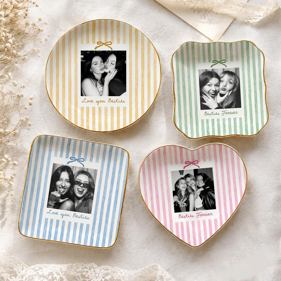 Four ceramic trinket dishes in yellow, green, blue, and pink with vertical stripes. Each dish features a central black and white photograph of two people, a small bow graphic, and the text Love you Besties or Besties Forever.