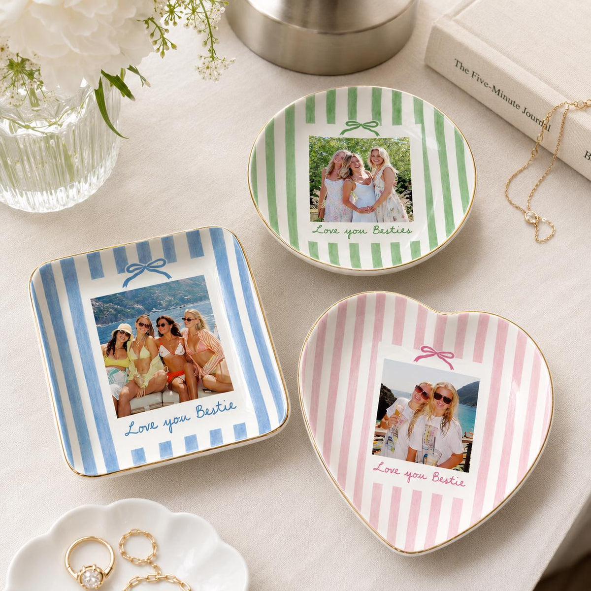 Three ceramic trinket dishes with gold-toned rims, featuring vertical stripes in blue, green, and pink. Each dish displays a custom photograph of friends and the printed text Love you Bestie, with a small bow graphic above the photo.