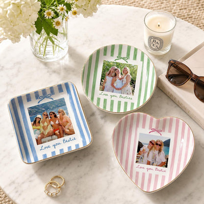 Three ceramic trinket dishes featuring vertical stripes in blue, green, and pink. Each dish displays a custom photograph of friends and the text Love you Bestie with a small bow graphic. The dishes are square, round, and heart-shaped.