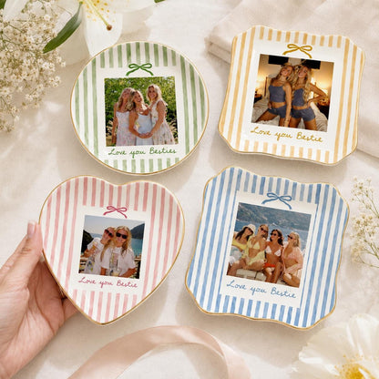 Four ceramic trinket dishes with striped patterns in green, yellow, pink, and blue. Each dish features a central photograph of friends, a small bow illustration above the photo, and the text Love you Bestie or Love you Besties.