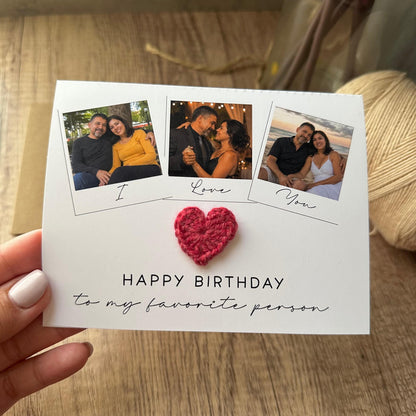 A white greeting card featuring three square photo frames with the text I Love You underneath them. A small red crocheted heart is attached to the center. The text HAPPY BIRTHDAY to my favorite person is printed below the heart.