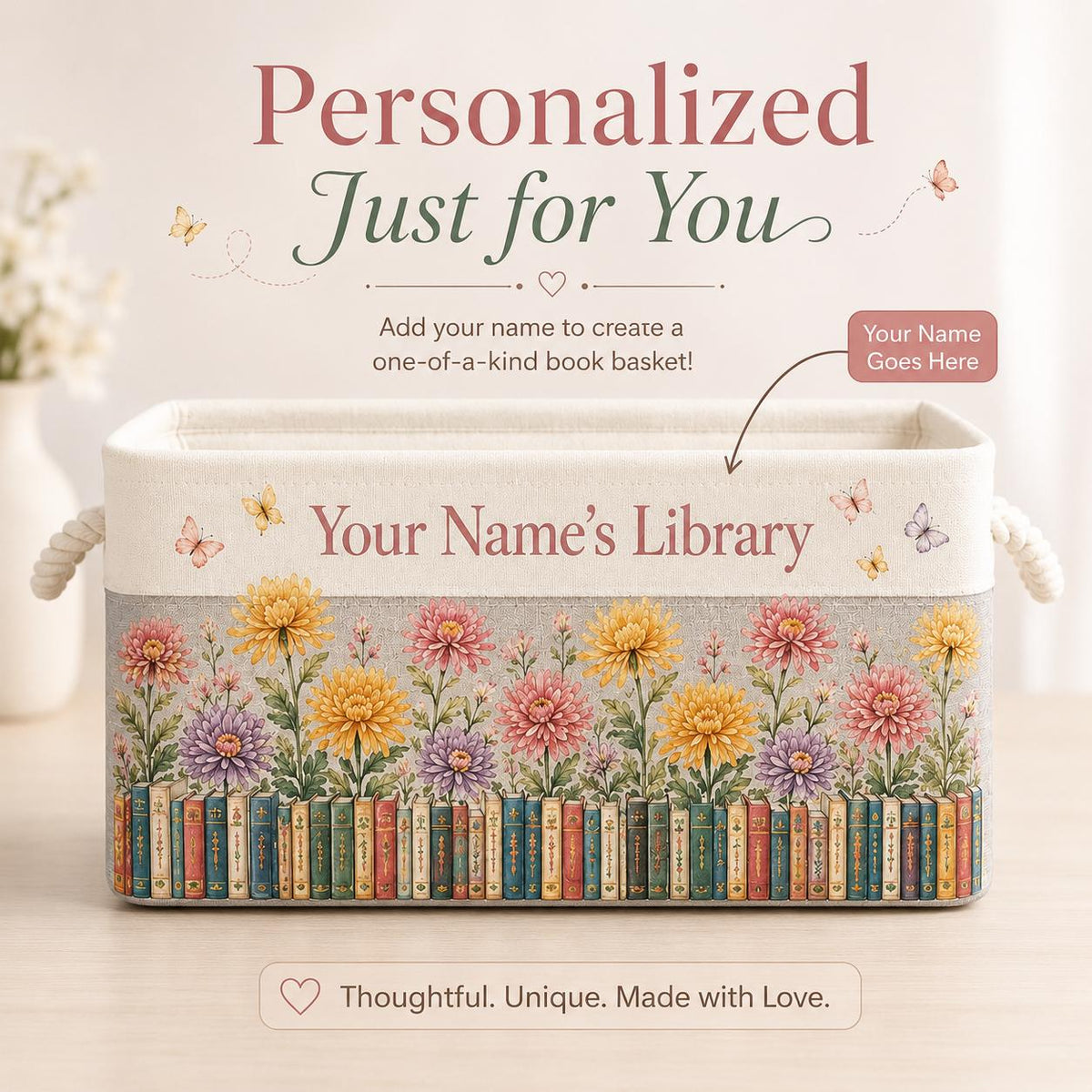 May include: A rectangular fabric storage basket with rope handles, featuring a printed design of colorful chrysanthemums above a row of vintage books. The text reads Personalized Just for You, Add your name to create a one-of-a-kind book basket!, Your Name Goes Here, Your Name’s Library, and Thoughtful. Unique. Made with Love.