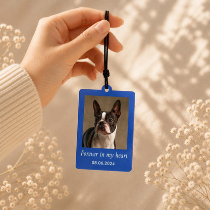 A rectangular blue hanging ornament featuring a photograph of a Boston Terrier dog. The text "Forever in my heart" and the date "08.06.2024" are printed in white below the image. The ornament hangs from a black cord.