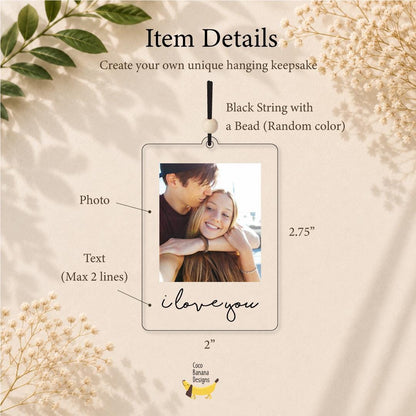 A rectangular clear acrylic hanging keepsake measuring 2 inches by 2.75 inches. It features a central photograph of two people, a black string with a bead, and the text "i love you" printed in black script at the bottom.