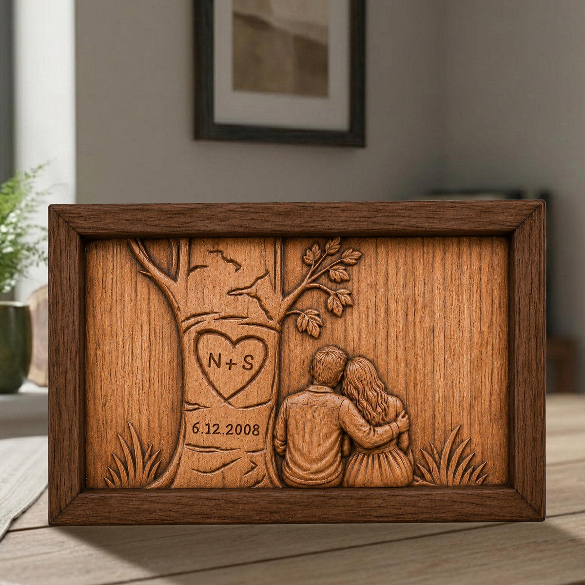 May include: A wooden framed artwork with a carved design. The artwork features a tree with a heart-shaped carving containing the initials "N+S" and the date "6.12.2008". Two figures are seated beneath the tree, embracing. The frame is a dark brown color.