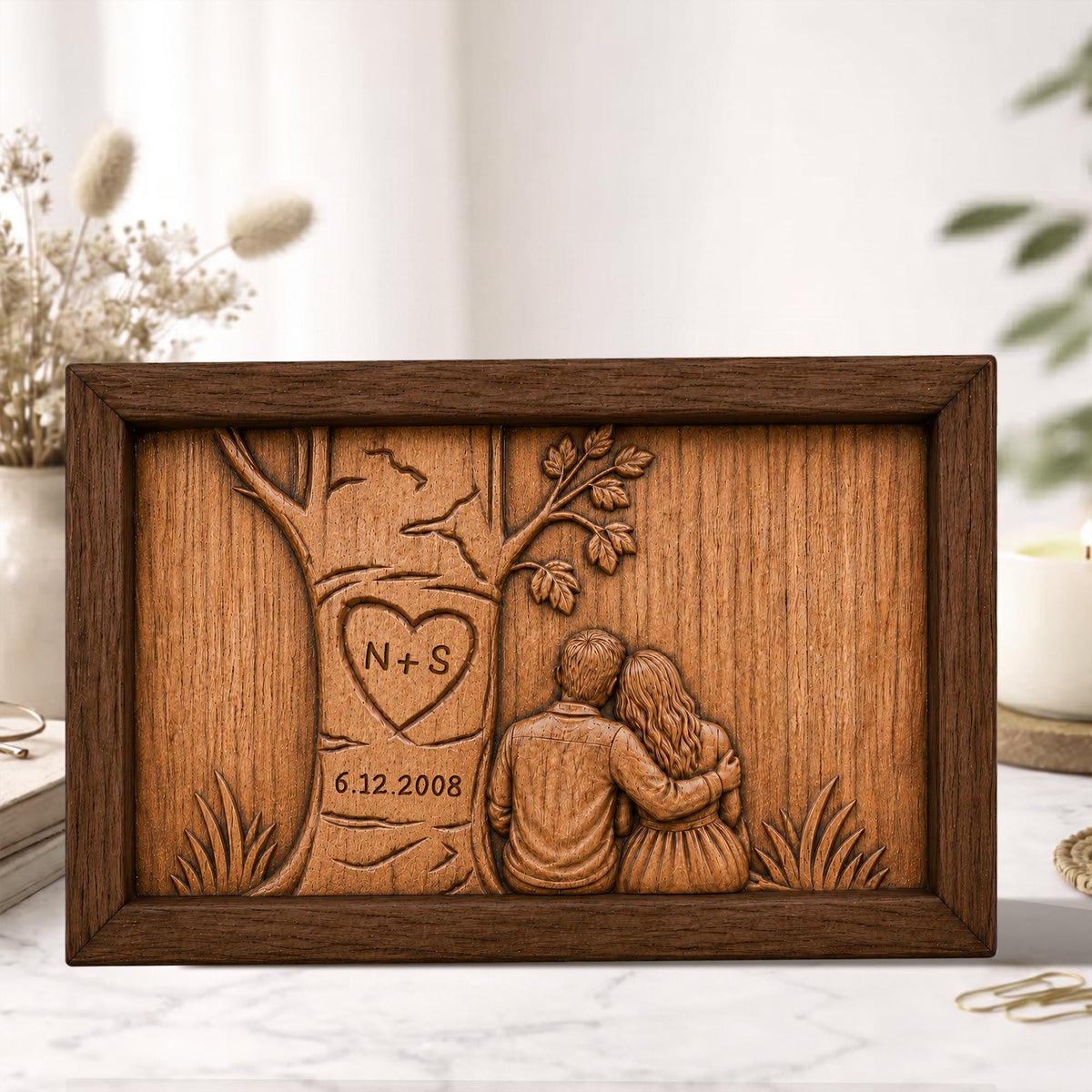 May include: A rectangular wooden plaque with a carved design. The design features a tree with a heart-shaped carving containing the initials "N+S" and the date "6.12.2008". Below the tree, a couple is depicted embracing. The plaque is framed in dark brown wood.
