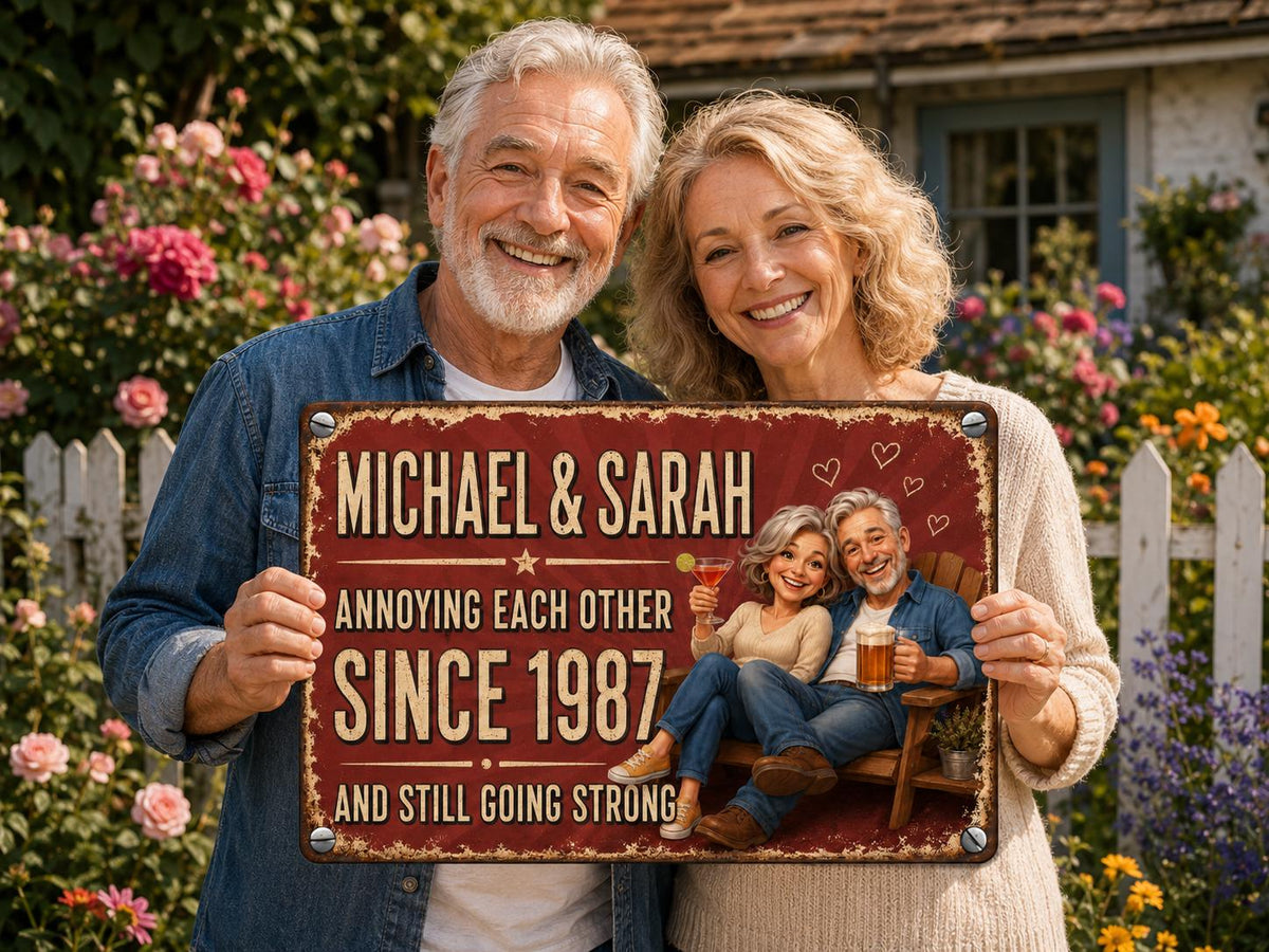 A rectangular metal sign with a distressed red background featuring the text "MICHAEL & SARAH ANNOYING EACH OTHER SINCE 1987 AND STILL GOING STRONG". The sign displays a cartoon illustration of a couple sitting on a wooden bench.
