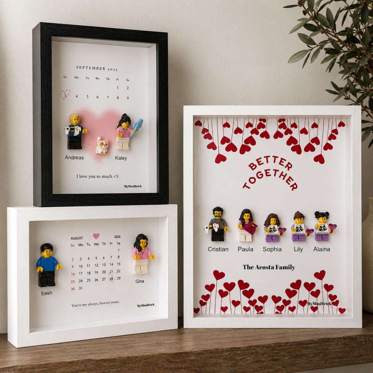 Three rectangular shadow box frames containing custom displays. Two frames feature printed calendars with minifigures and names, while the third displays the text Better Together with five minifigures and red heart illustrations.
