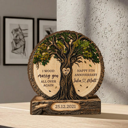 May include: A circular wooden plaque featuring a carved tree with green leaves, text reading I WOOD marry you ALL OVER AGAIN and HAPPY 5TH ANNIVERSARY Julia and Matt, a heart with J M, and a rectangular base with the date 25.12.2021 engraved on it.