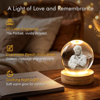 A clear glass sphere night light featuring a 2D laser-engraved portrait of an elderly person inside. The sphere rests on a round, light-colored beech wood base with the engraved text Happy Birthday Granny and a warm internal glow.